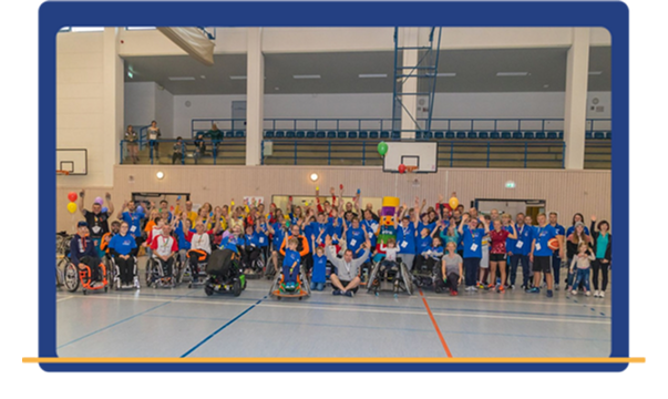 Große Gruppe von Menschen mit und ohne Handicap bei einer Veranstaltung in einer Turnhalle – Symbol für gemeinsames Engagement und gelebte Inklusion.